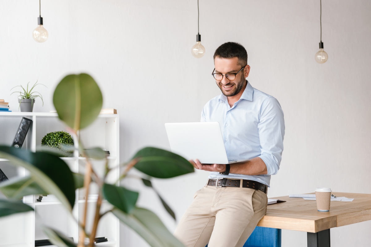 Junger Mann mit Laptop - hochgekrempeltes Business Hemd